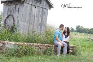 Couple sitting on stone wall in front of a barn in New England